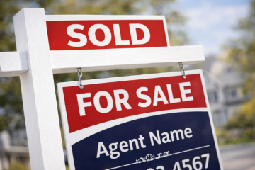 Close-up of a real estate SOLD rider on an L-post sign, showing bold sans serif typography readable at street distance
