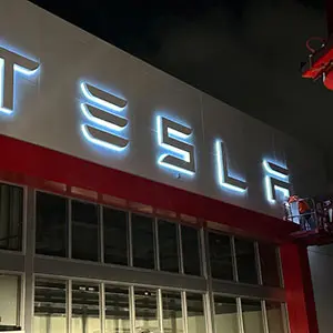 Sign Tech using our bucket truck to repair the Channel Letters mounted on a TESLA automobile dealership's Building.